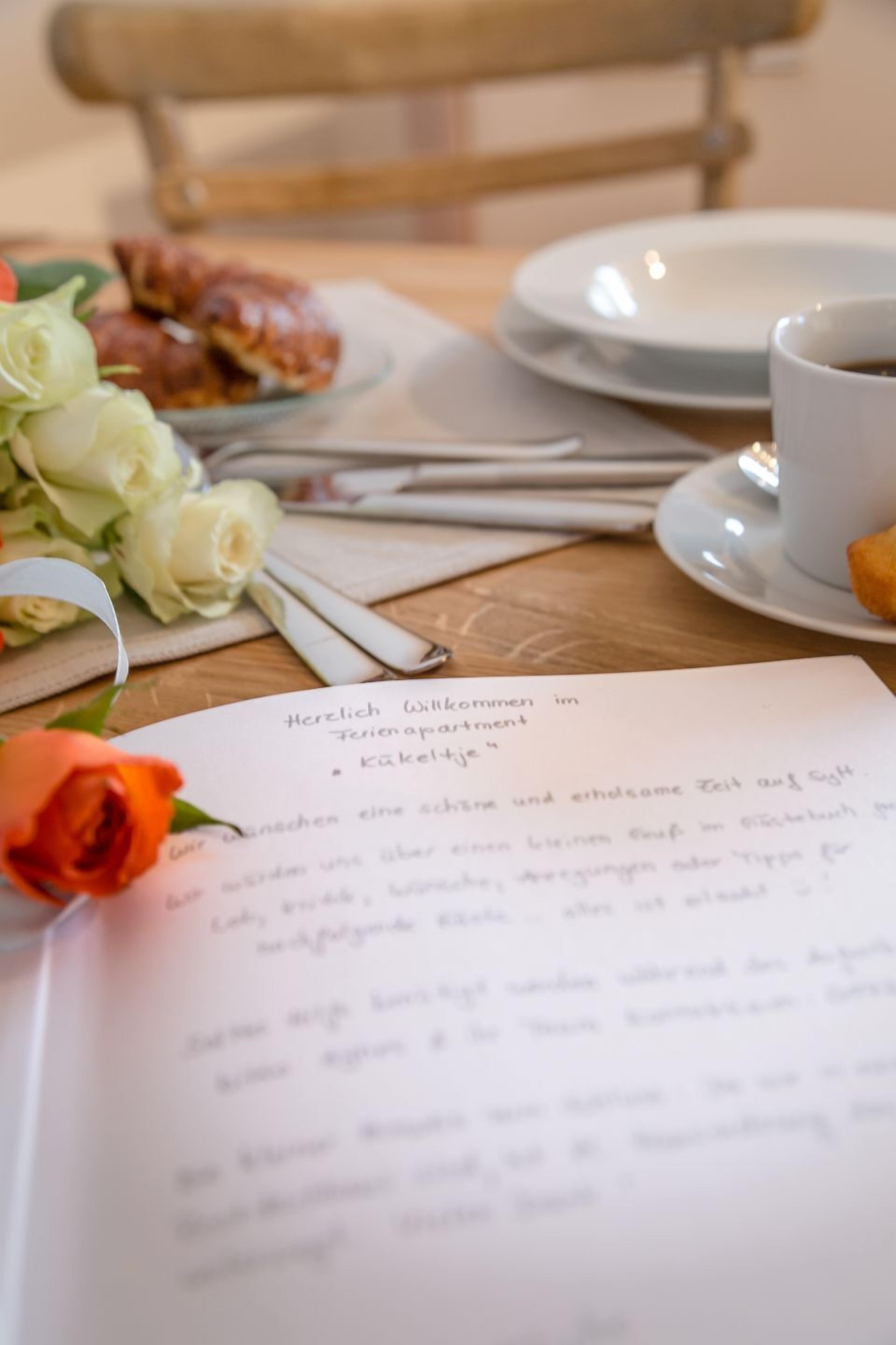 Una mesa con un menú, una taza de café, un plato de comida y una rosa.
