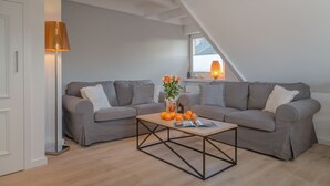 Ein modernes Wohnzimmer mit zwei grauen Sofas, einem Couchtisch und einer Stehlampe.