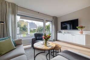 A modern living room with a sofa, a coffee table, and a TV mounted on the wall.