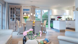Een moderne keuken met witte kasten en een eethoek met rieten stoelen en een tafel.