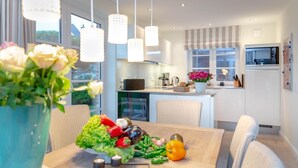 Een moderne keuken met witte kastjes, een centraal eiland en hanglampen.