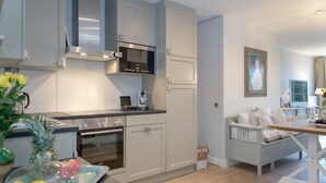 Une cuisine moderne équipée d’appareils électroménagers en acier inoxydable, un coin repas avec une table en bois et un espace salon confortable avec un banc rembourré.