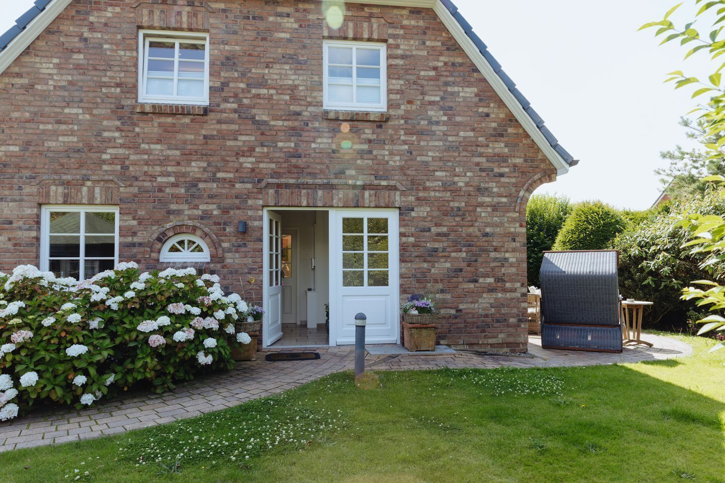 A two-story brick house with a front door, two windows, and a small porch area.