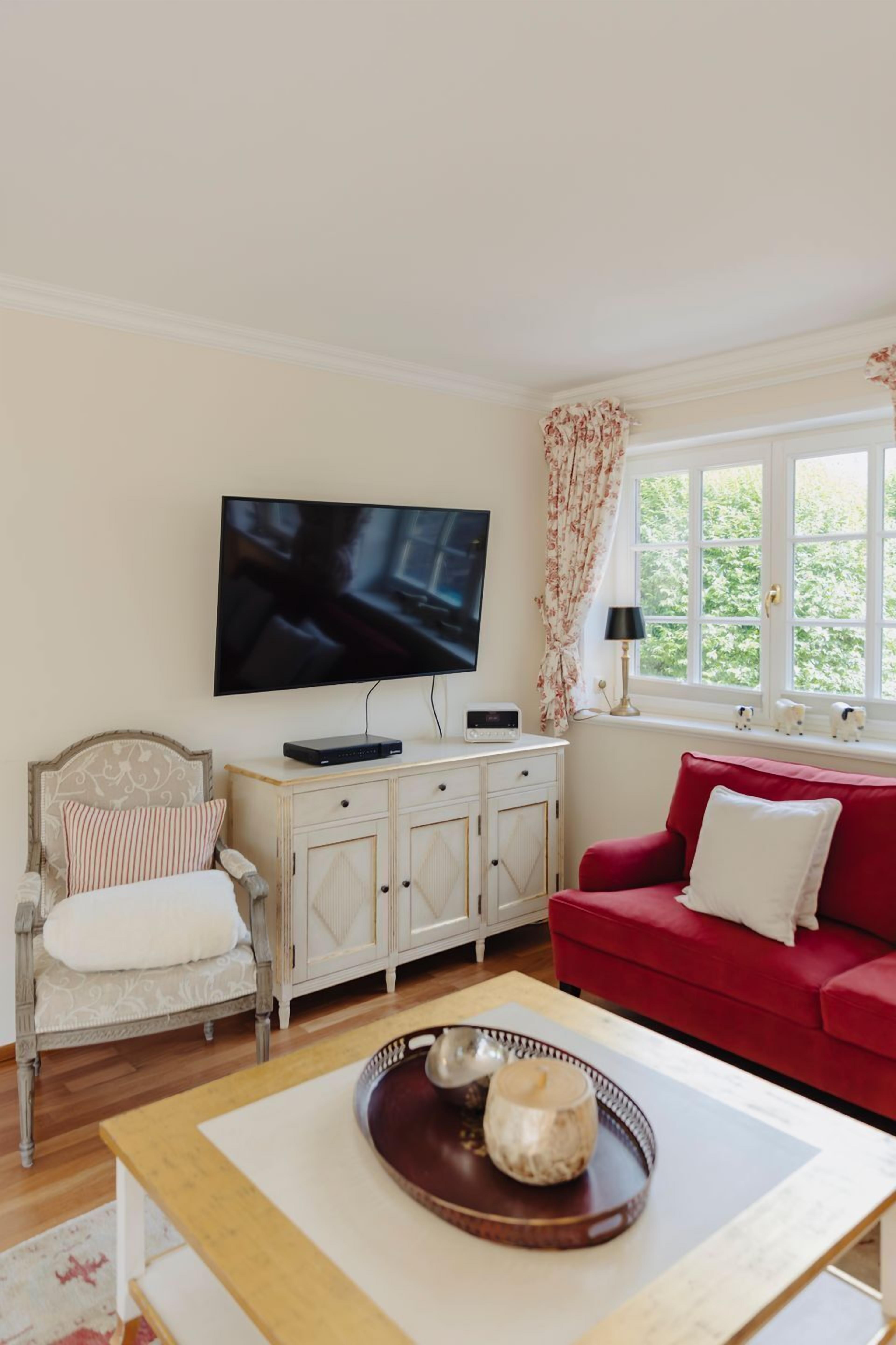 A living room with a television, a red sofa, a wooden coffee table, and a cabinet.