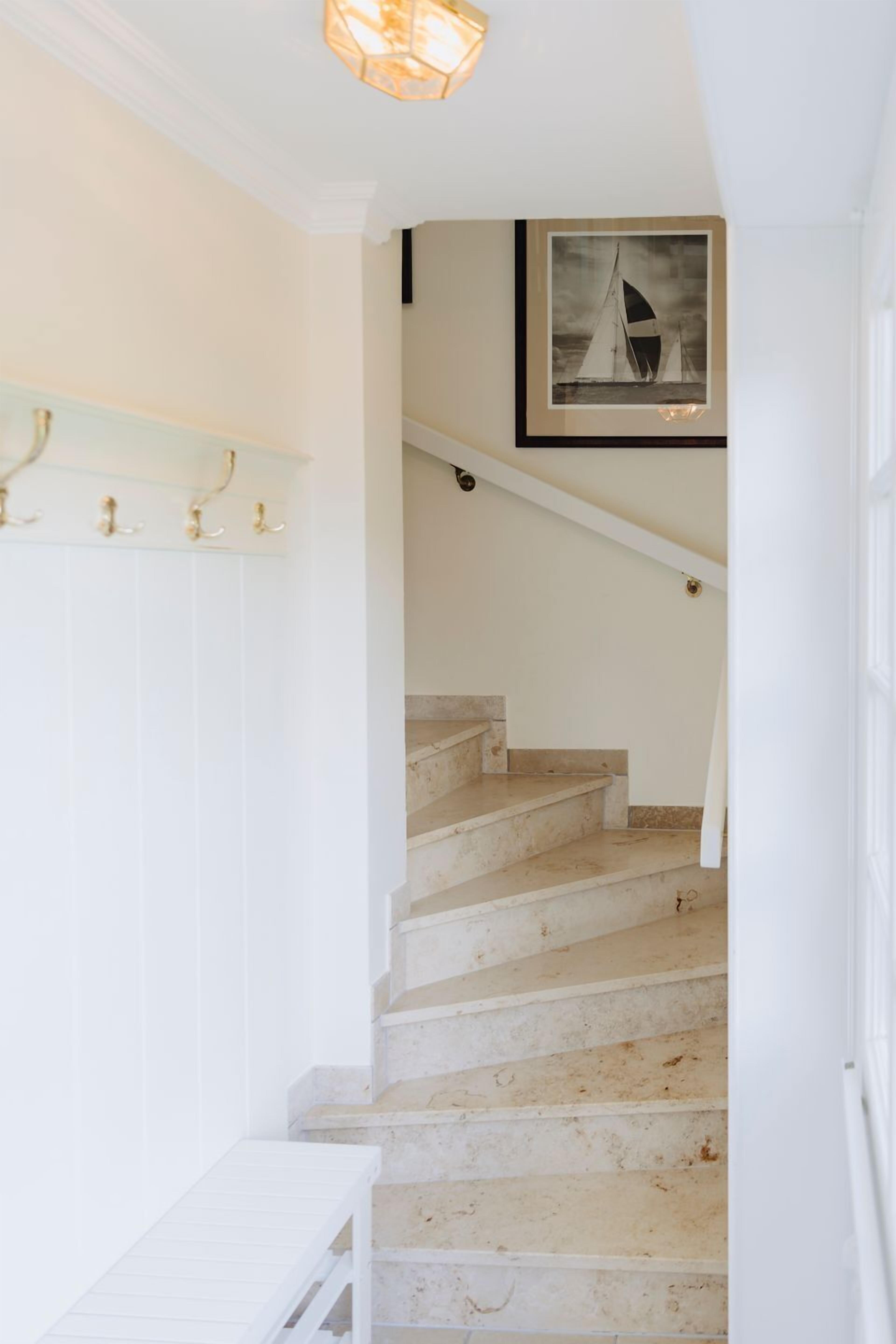 A staircase with white walls and a framed picture of sailboats.