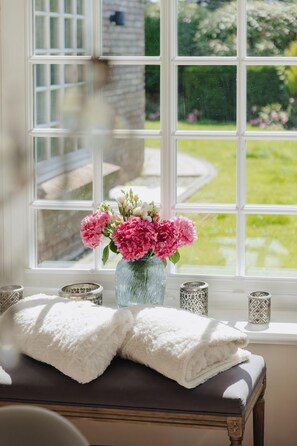 A window with a view of a garden, a vase with flowers, and a folded towel on a bench. - House Traumzeit Family - Our Traumzeit-Family is comfortable and (Wenningstedt-Braderup (Sylt))