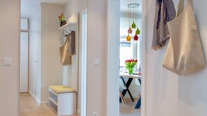 Un couloir moderne et bien éclairé, avec un banc, un miroir et un porte-manteau suspendu.