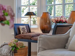 A cozy seating area with a sofa and armchairs, a lamp, and a vase with flowers.