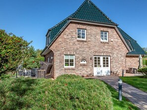 Et murstenshus med en markant taghældning, en fordør og en lille veranda.