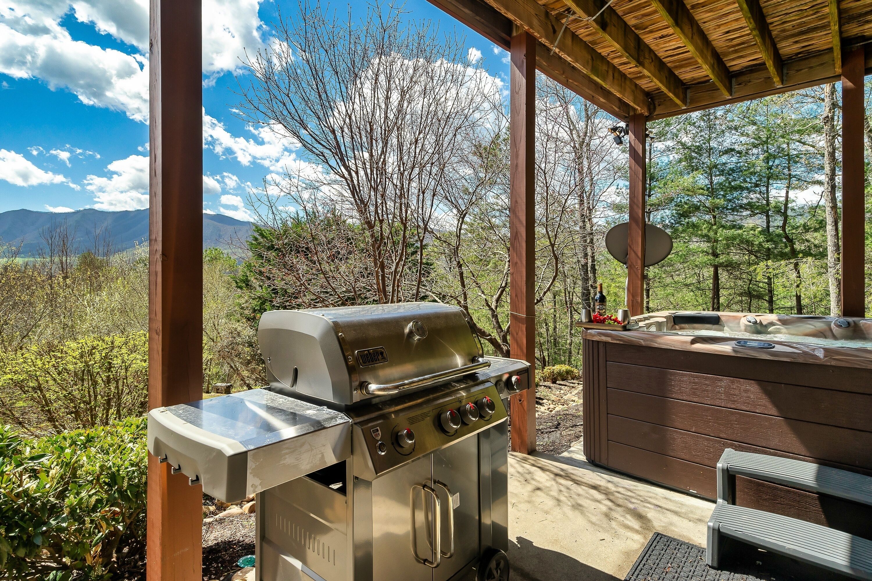An outdoor patio with a stainless steel grill and a hot tub.