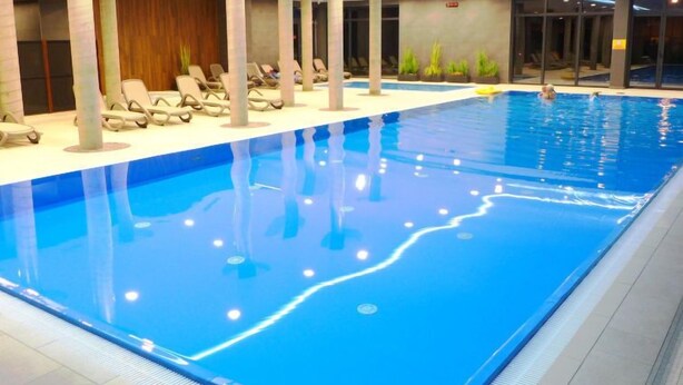 An indoor swimming pool with lounge chairs and a wooden wall. - Apartment A 204 by Interhome (Kolobrzeg)