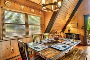 A wooden dining room with a long table, chairs, and a chandelier.