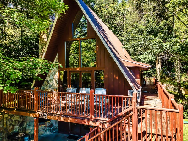 A wooden cabin with a balcony, surrounded by trees.