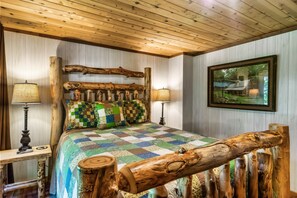 A rustic bedroom with a wooden headboard, a quilted bedspread, and two bedside lamps.