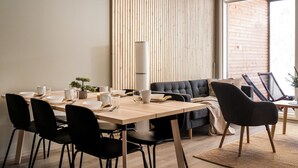 Un comedor moderno con una mesa de madera, sillas negras y un sofá gris.