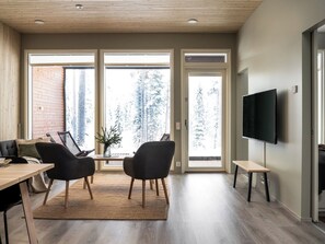 A modern living room with a dining area, large windows, and a flat-screen TV. - Vuokatin loiste 9 a 3 by Interhome (Sotkamo)