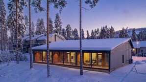 Un edificio moderno con amplias ventanas de vidrio, rodeado de árboles cubiertos de nieve.