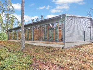 A modern building with large glass windows, a wooden deck, and a metal roof. - Vuokatin loiste 9 a 3 by Interhome (Sotkamo)