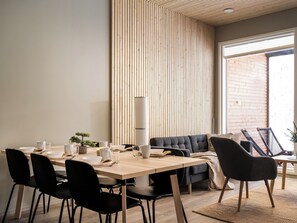 A modern dining area with a wooden table, black chairs, and a grey sofa. - Vuokatin loiste 9 a 3 by Interhome (Sotkamo)