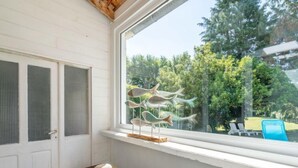 A room with a window overlooking a garden, a wooden bench with a hat, and a decorative metal sculpture. - Ti ar Stang by Interhome (Esquibien)
