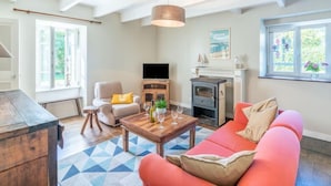 A living room with a fireplace, a sofa, a coffee table, and a television. - Ti ar Stang by Interhome (Esquibien)