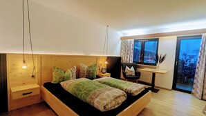 Un dormitorio moderno con una cama de madera, mesitas de noche, un escritorio y un ventanal con vistas.