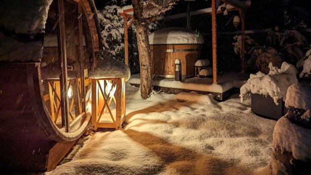 Un edificio rústico de madera con una gran caseta de control y una pequeña cabaña, ambos rodeados de nieve.