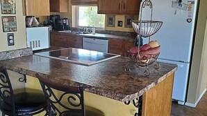 A kitchen with a granite countertop, a built-in oven, a refrigerator, and a sink. - Sunland Cottage in 55+ Golf Community (Mesa)