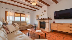 A living room with a sofa, a wooden coffee table, a fireplace, and a television mounted on the wall.