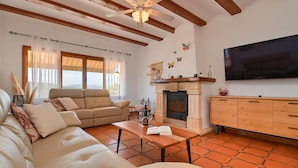 A living room with a sofa, a wooden coffee table, a fireplace, and a television mounted on the wall.