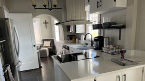 A modern kitchen with a central island, white cabinetry, and stainless steel appliances. - Beautiful Restored Victorian Home (Pueblo)