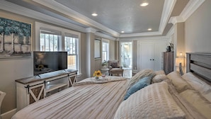 A spacious bedroom with a large bed, a television, and a painting on the wall. - Beautiful Restored Victorian Home (Pueblo)