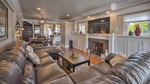 A spacious living room with a large leather sofa, a dining area, and a kitchen with a fireplace. - Beautiful Restored Victorian Home (Pueblo)