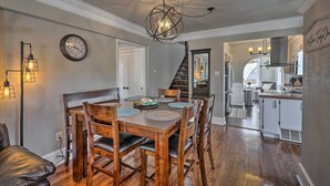 A dining area with a wooden table and chairs, a chandelier, and a clock on the wall. - Beautiful Restored Victorian Home (Pueblo)