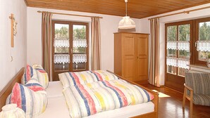 Un dormitorio con cama de madera, un armario y una ventana con cortinas.