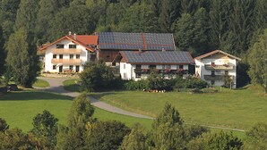 Un edificio residencial de varios pisos, con paneles solares en el techo y un paisaje verde circundante.