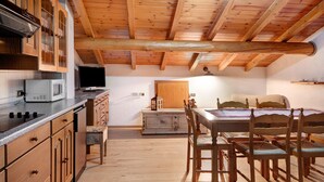 A wooden interior with a kitchen, dining area, and a bed. - Apartment 'Baita Franz Mansarda 1' with Mountain View, Garden and Wi-Fi (Livigno)