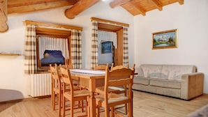 A cozy room with a wooden dining table, chairs, a sofa, and a painting on the wall. - Apartment 'Baita Franz Mansarda 1' with Mountain View, Garden and Wi-Fi (Livigno)