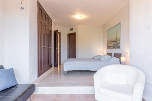 Un dormitorio con cama, una silla, un sofá y un armario.
