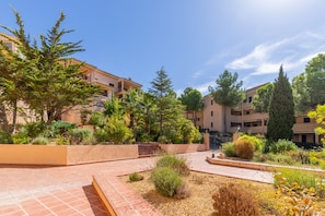 Un patio con edificios, un sendero central y diversas plantas.