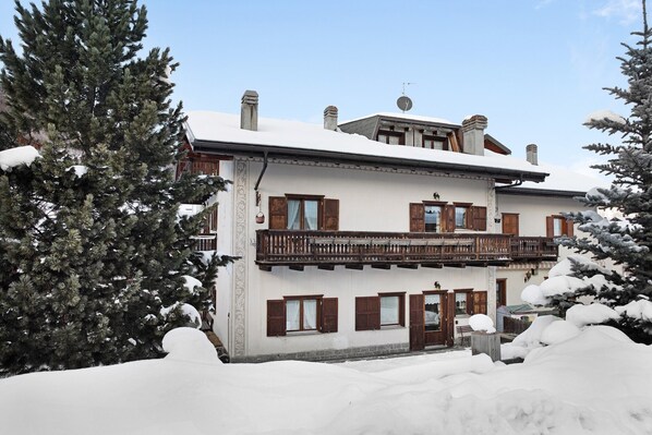 A two-story building with a balcony, surrounded by snow-covered trees. - Apartment "Baita Franz 3" with Mountain View, Garden and Wi-Fi (Livigno)