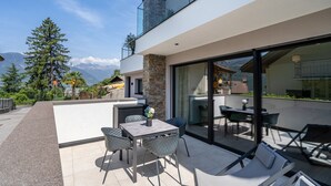 A modern outdoor patio with a dining area, seating, and a view of mountains. - Apartment "Videre Lodge Wasserfall" with Mountain View, Wi-Fi & Terrace (Gargazon)