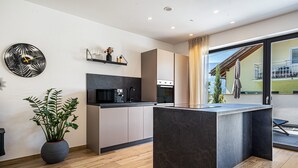 A modern kitchen with a central island, built-in appliances, and a large window. - Apartment "Videre Lodge Wasserfall" with Mountain View, Wi-Fi & Terrace (Gargazon)