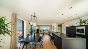 A modern kitchen with a central island, dining area with chairs, and large windows offering a city view. - Apartment "Videre Penthouse Lodge Exclusive" with Mountain View, Wi-Fi & Terrace (Gargazon)