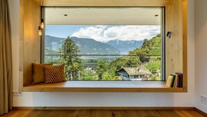 A room with a large window, wooden bench, and books. - Apartment "Videre Penthouse Lodge Exclusive" with Mountain View, Wi-Fi & Terrace (Gargazon)