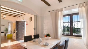 A dining area with a white table, chairs, a teapot, and a bowl of fruit. - "Vila Caracol" with Pool, Tennis Court, A/C & Wi-Fi (Guia)