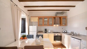 A modern kitchen with white cabinets, a dining table with chairs, and a washing machine. - "Vila Caracol" with Pool, Tennis Court, A/C & Wi-Fi (Guia)