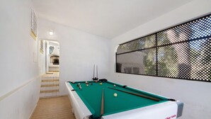 Ein Billardtisch mit Kugeln, eine Treppe und eine Wand mit Gitterwerk.