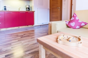 A wooden table with a wooden toy in a room with a red cabinet and a beige sofa.