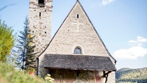 A stone church with a bell tower, a wooden door, and a window. - Holiday Apartment 'Riegelehof 1' with Balcony, Garden & Wi-Fi (Lajen)